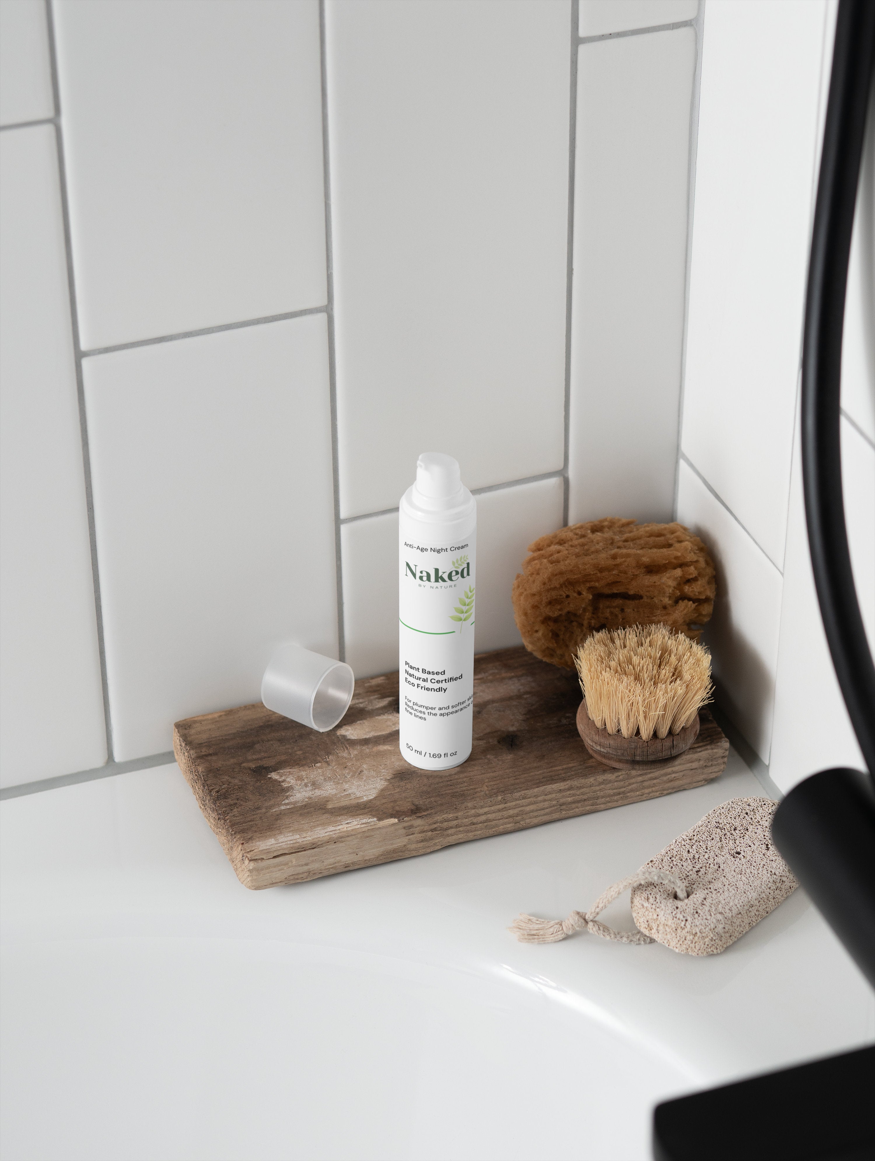 Plant-based anti-age night cream on rustic wood tray with natural bath brush and sponge in white tiled bathroom