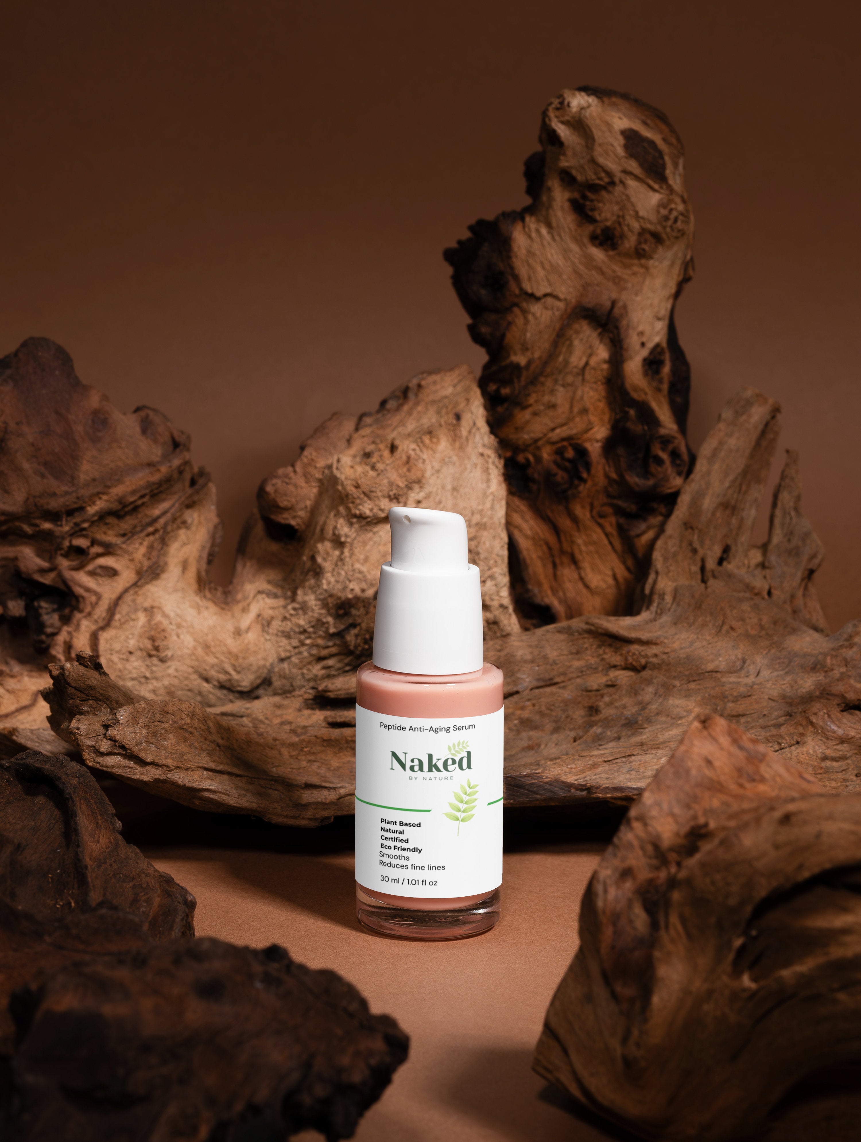 Plant-based peptide anti-aging serum in glass bottle with dropper, surrounded by natural driftwood, eco-friendly skincare