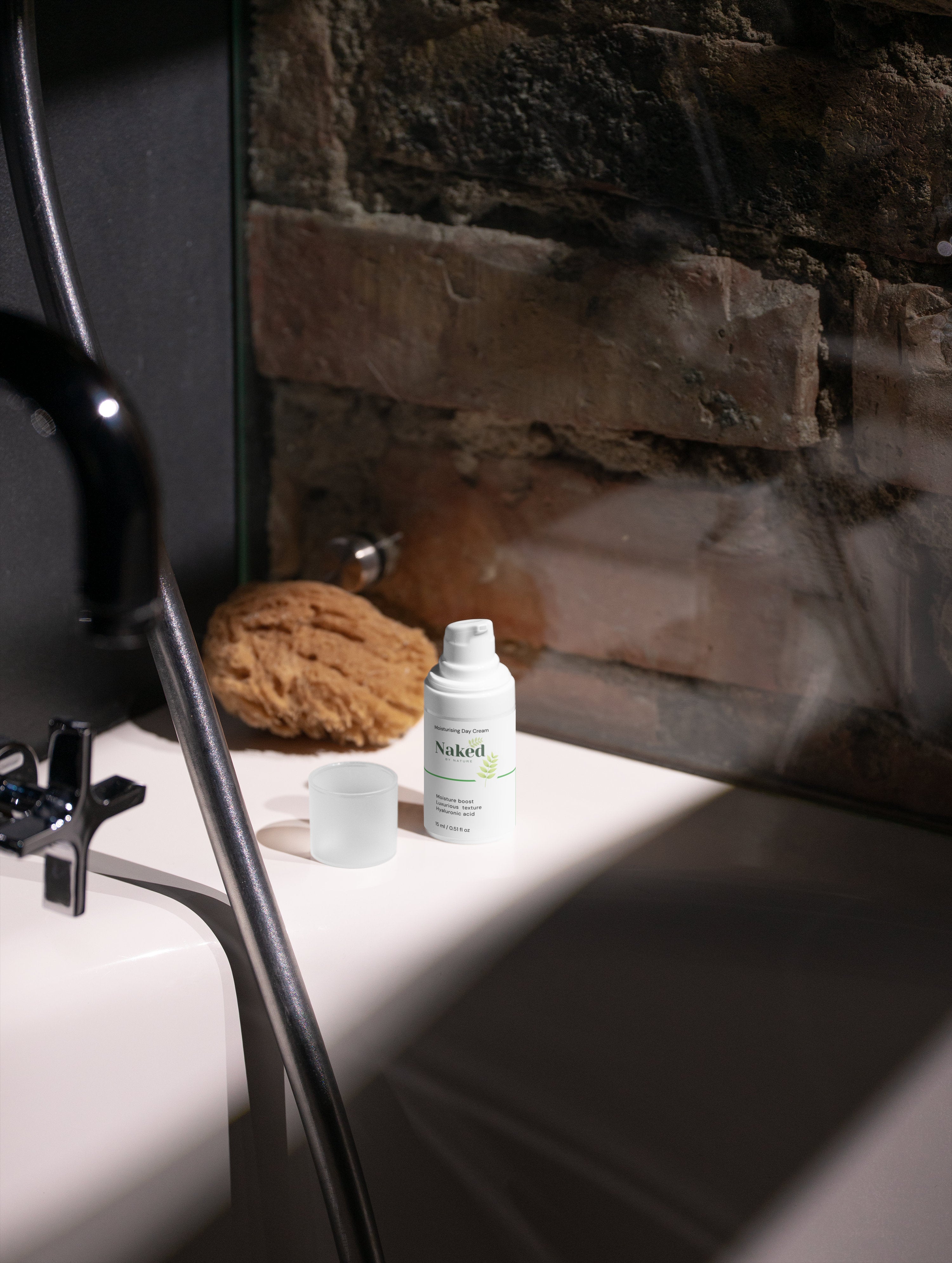 Naked by Nature Moisturising Day Cream with hyaluronic acid on bathroom counter beside natural sponge