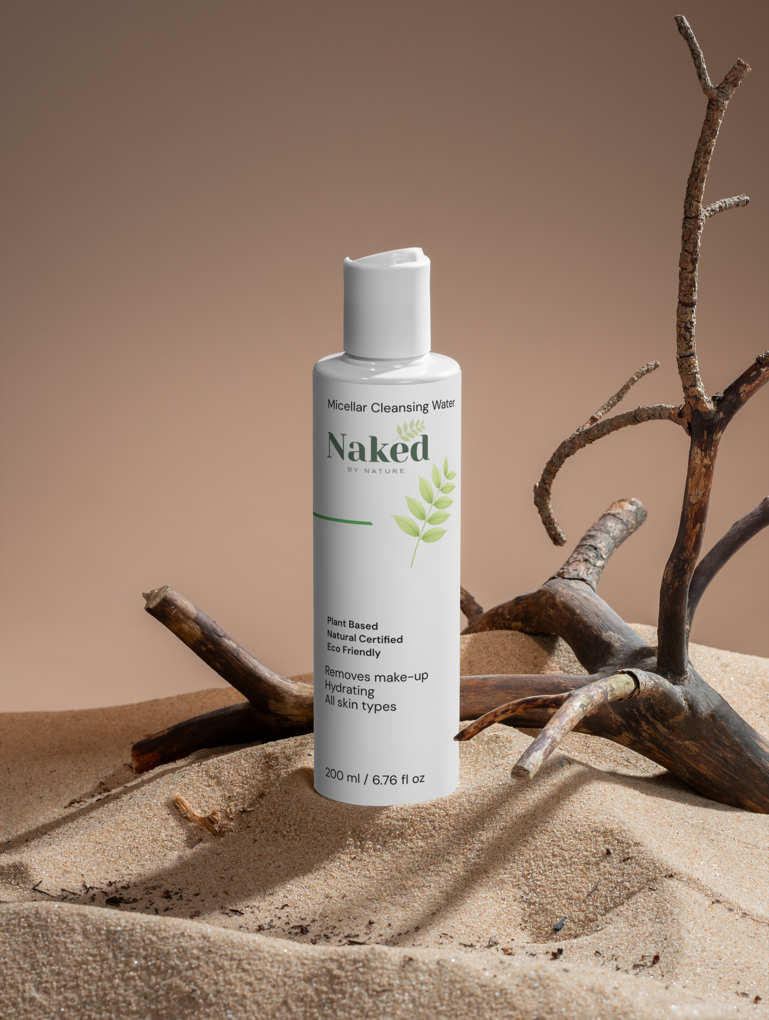 Naked by Nature Micellar Cleansing Water bottle on sand with driftwood, plant-based, hydrating, eco-friendly for all skin types