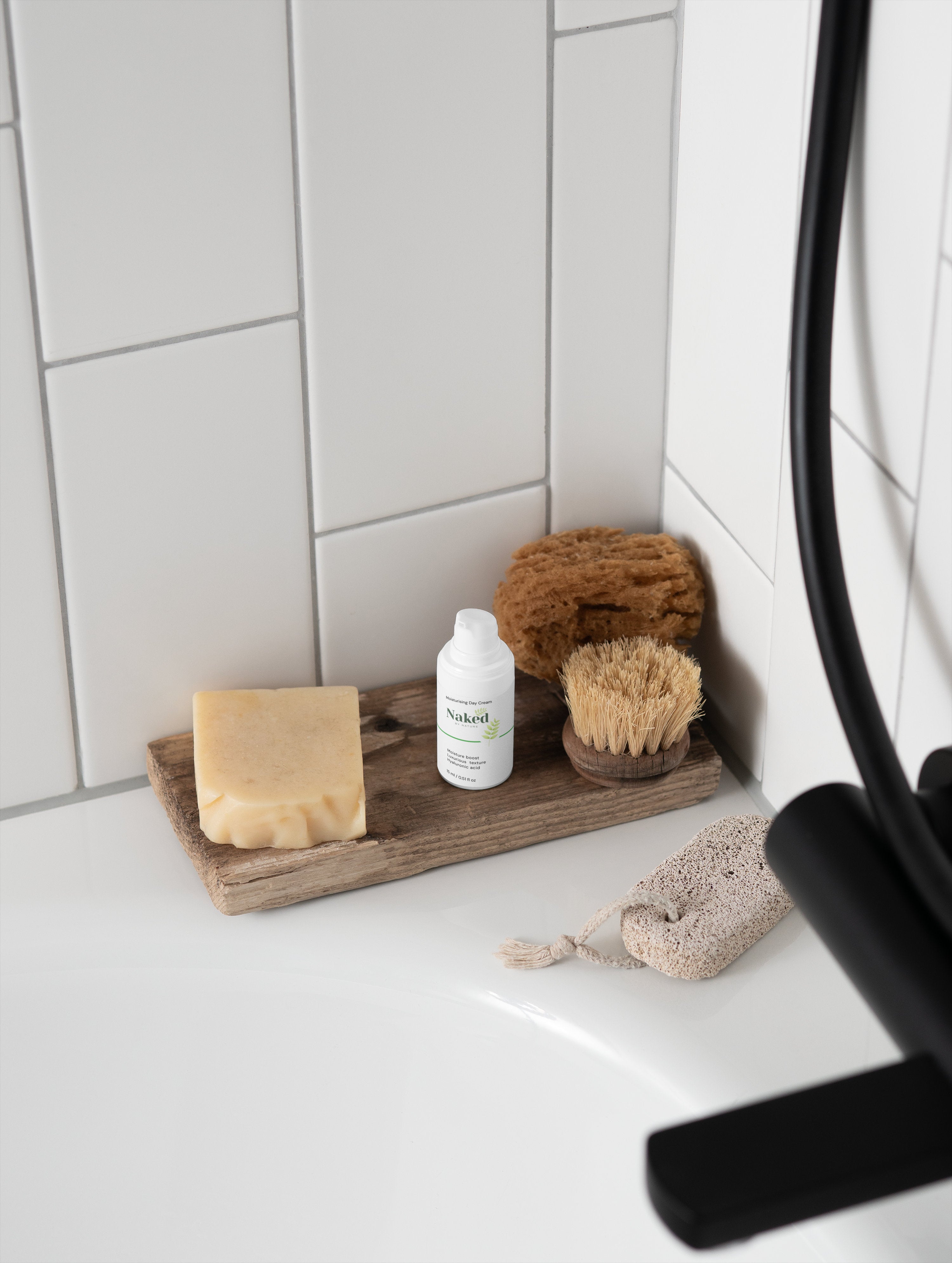 Naked by Nature Moisturising Day Cream with natural soap, brush, and sponge on wooden tray in bathroom
